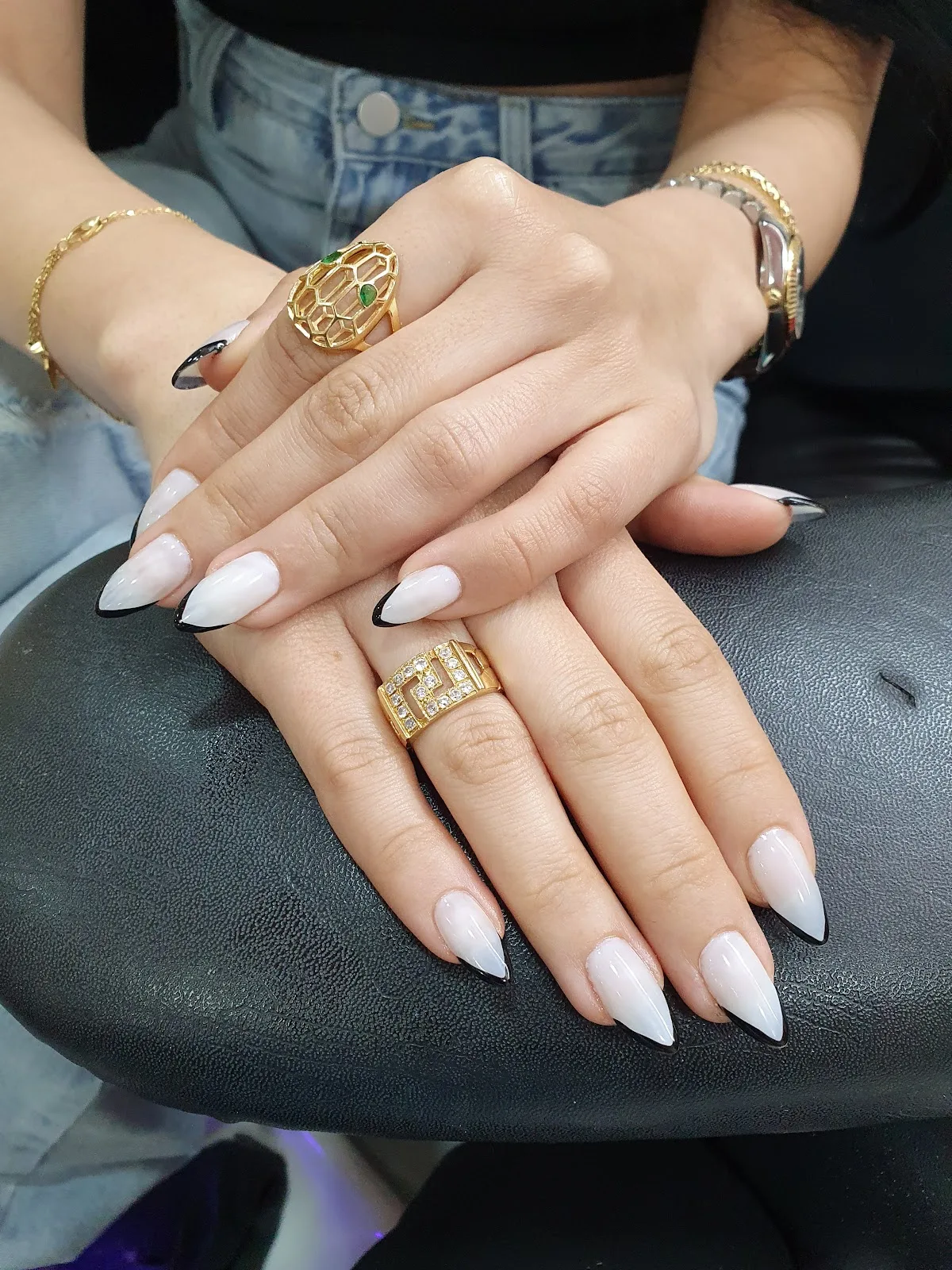 Glossy almond nails with black and gold French tips by Unique Beauty Salon