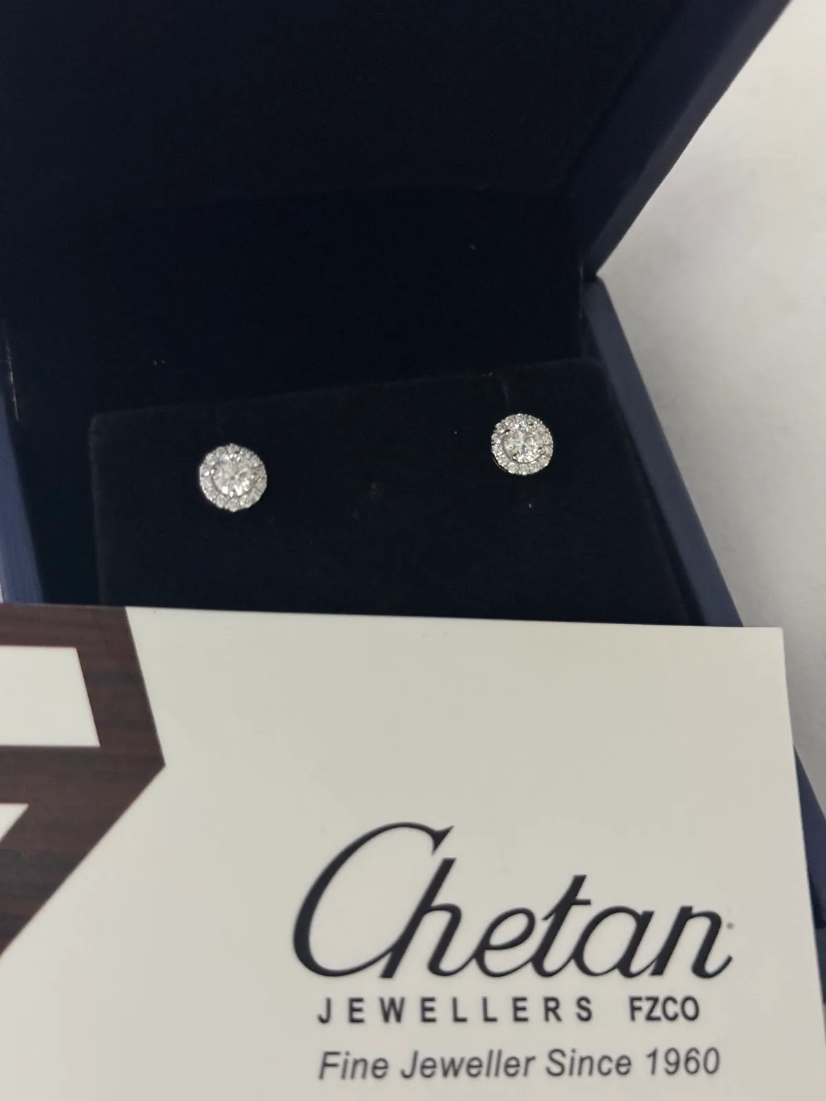 Diamond halo stud earrings presented in a Chetan Jewellers gift box