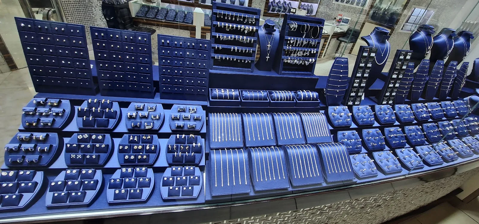 An in-store display of diamond earrings, studs and fine chains on navy stands