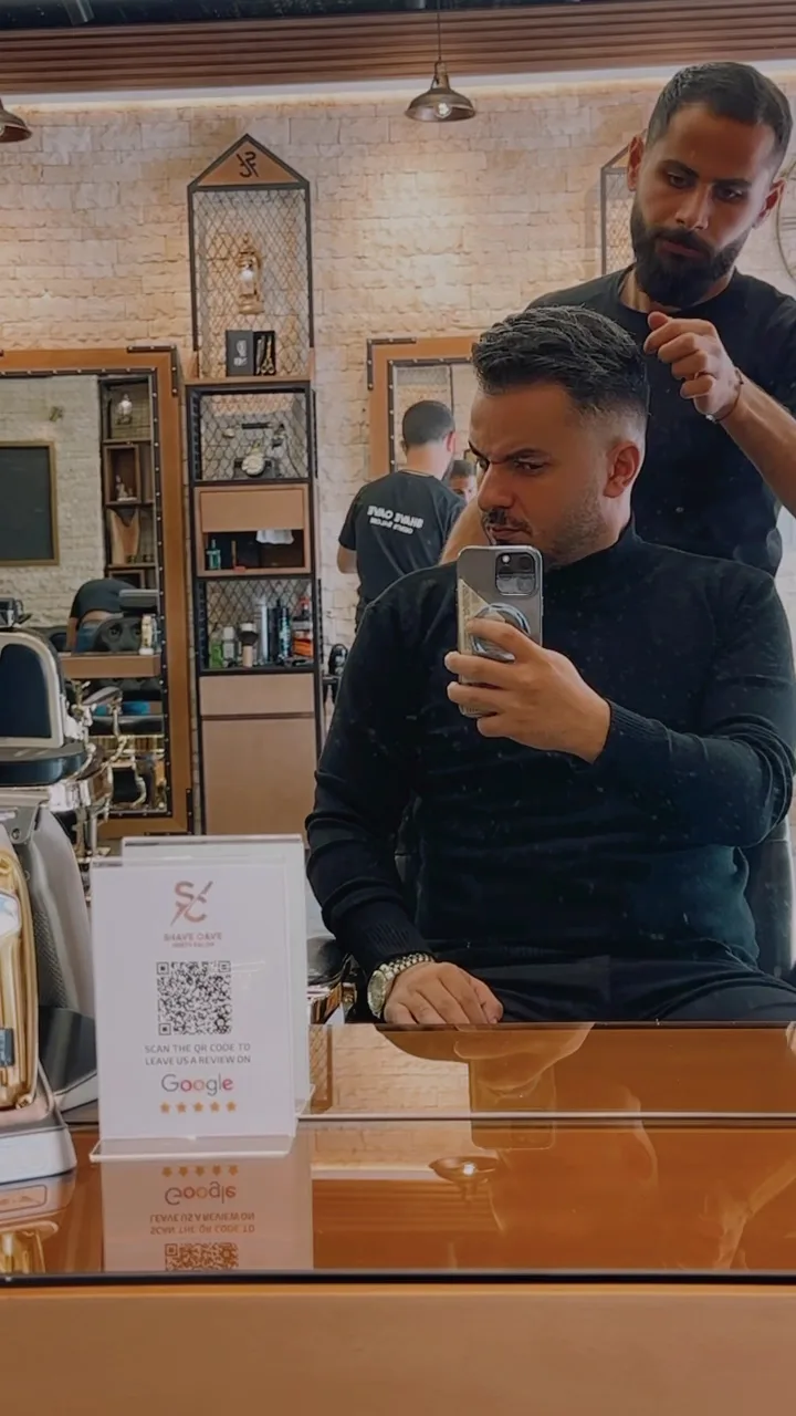 Barber styling a client's hair at the mirror inside Shave Cave