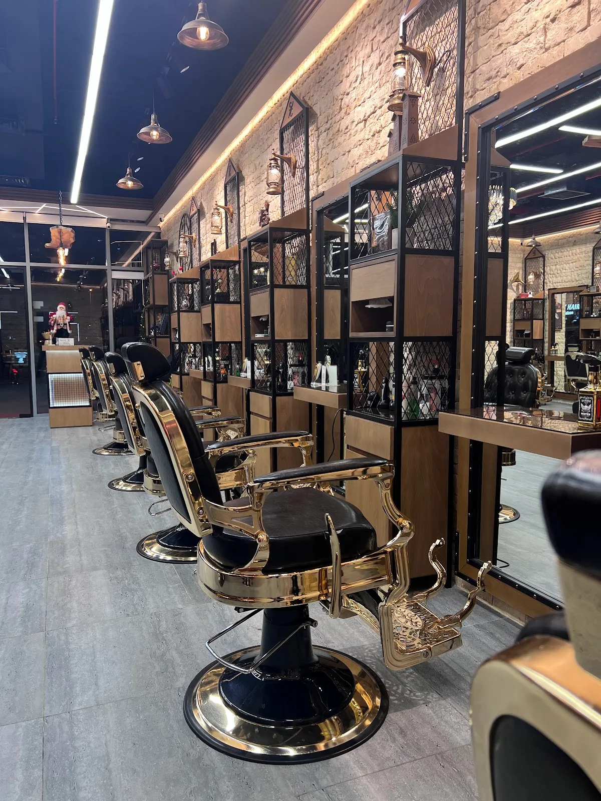 Row of black-and-gold barber chairs along an exposed-brick wall inside Shave Cave Gents Salon