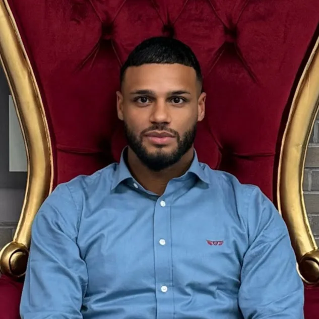 A client with a fresh fade seated in a red-and-gold throne chair at Shave Cave