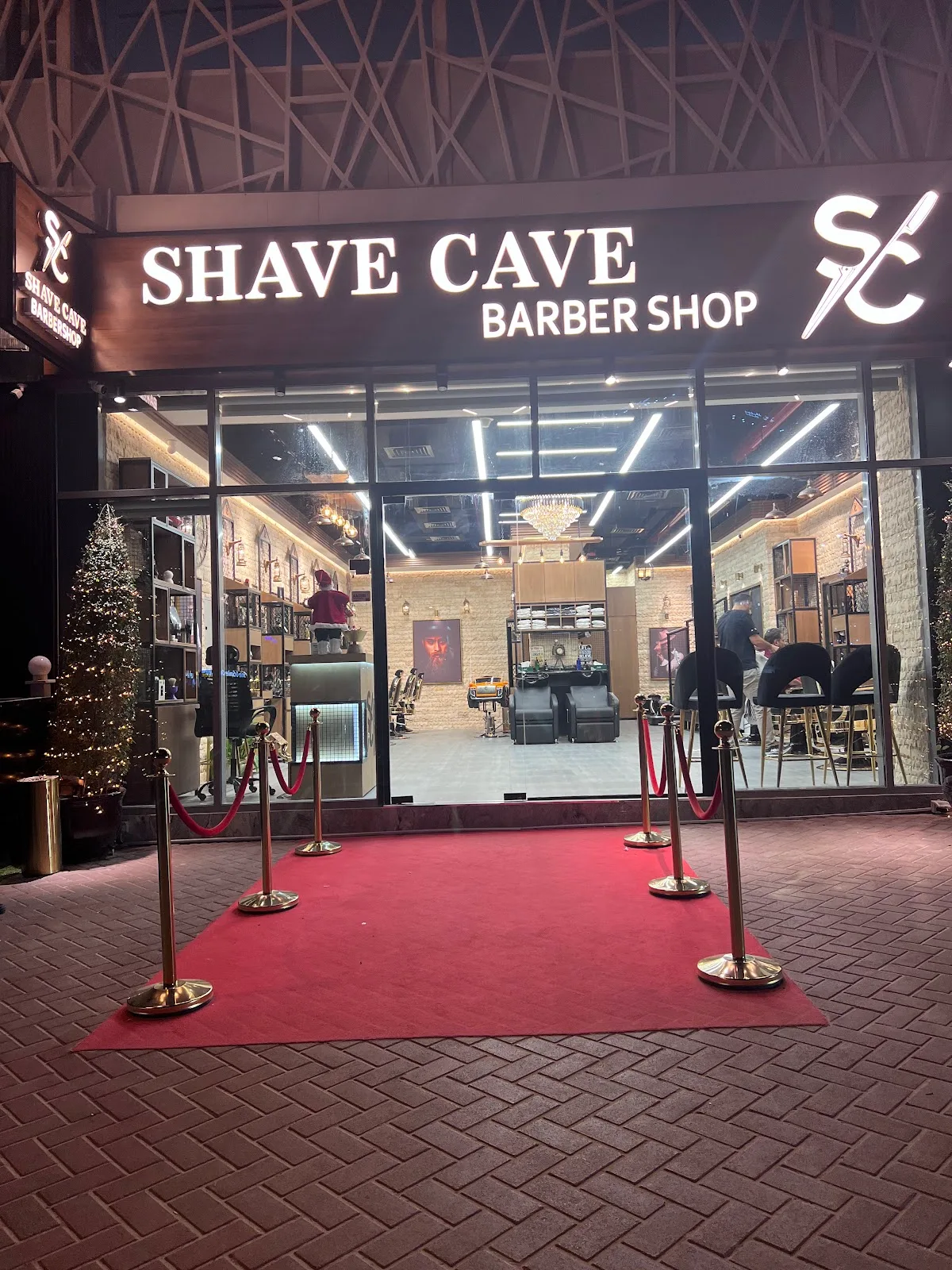 Shave Cave Barber Shop storefront at night with a red-carpet entrance