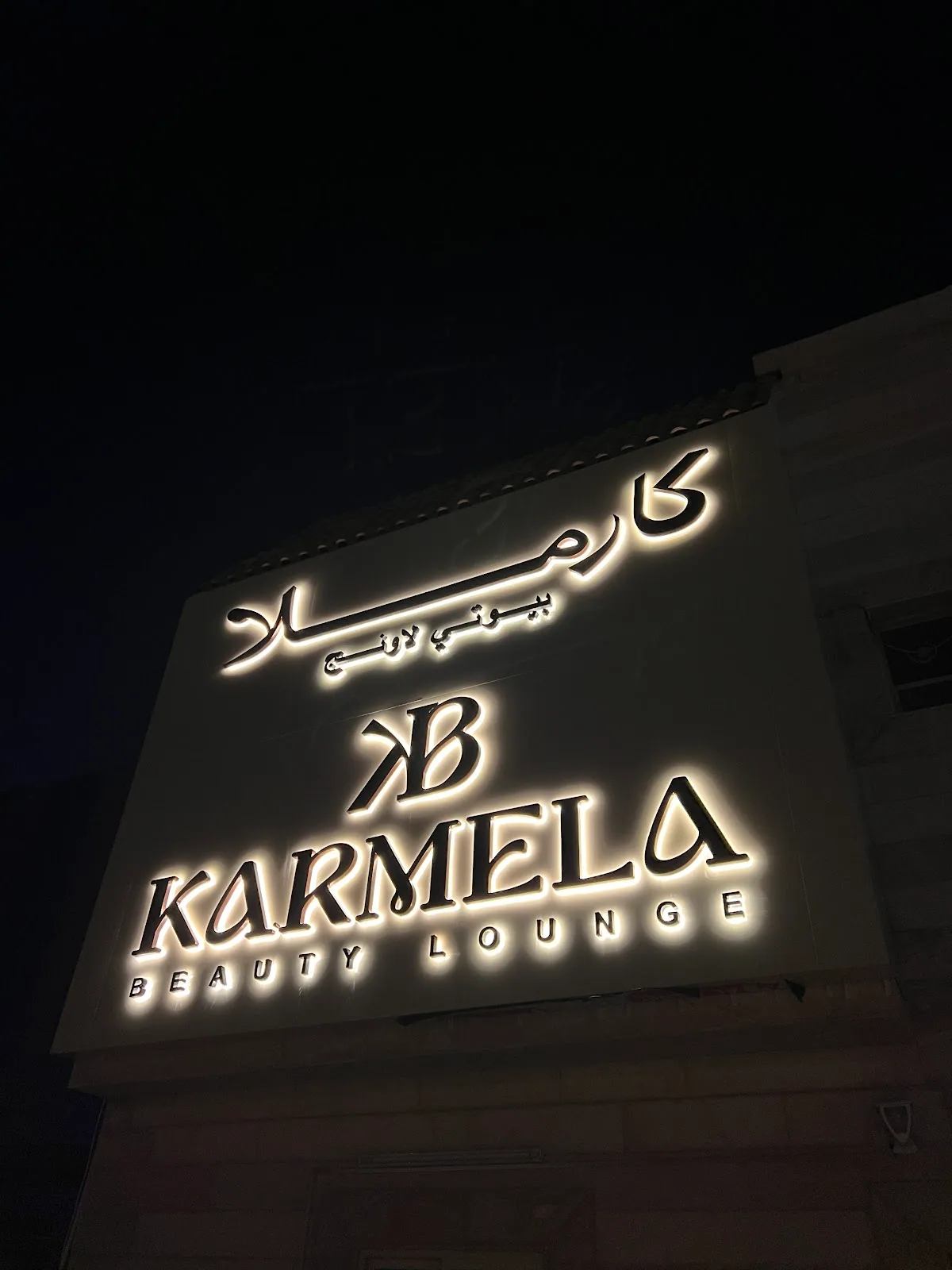 Illuminated Karmela Beauty Lounge storefront sign at night in Al Warqa, Dubai