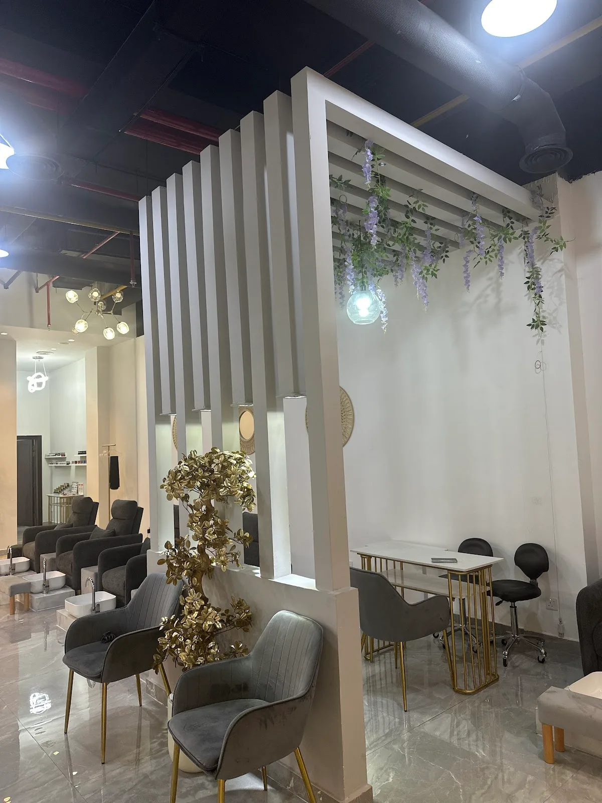 Bright interior of N Dot K Beauty Lounge with marble floors, gold-trimmed manicure stations and hanging wisteria