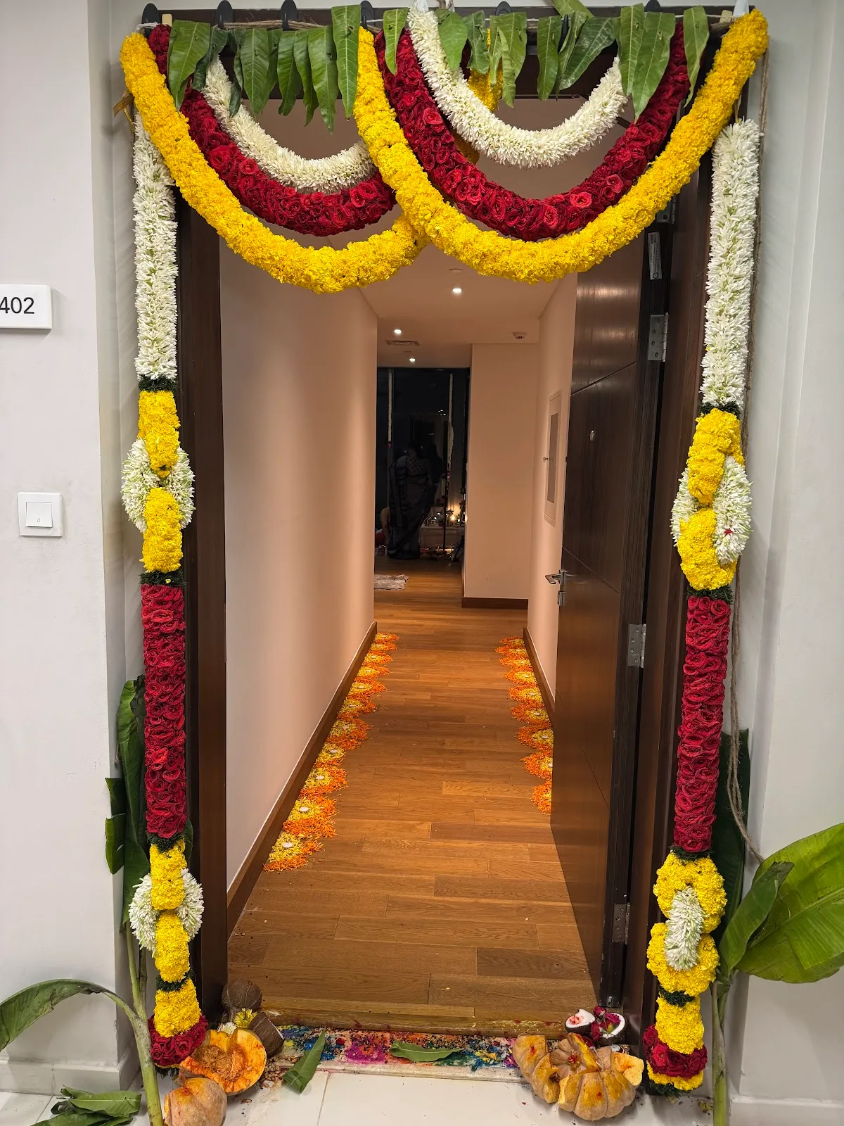 A doorway decorated with a lavish marigold, rose and jasmine garland arch by Perumal Flowers for a home function.