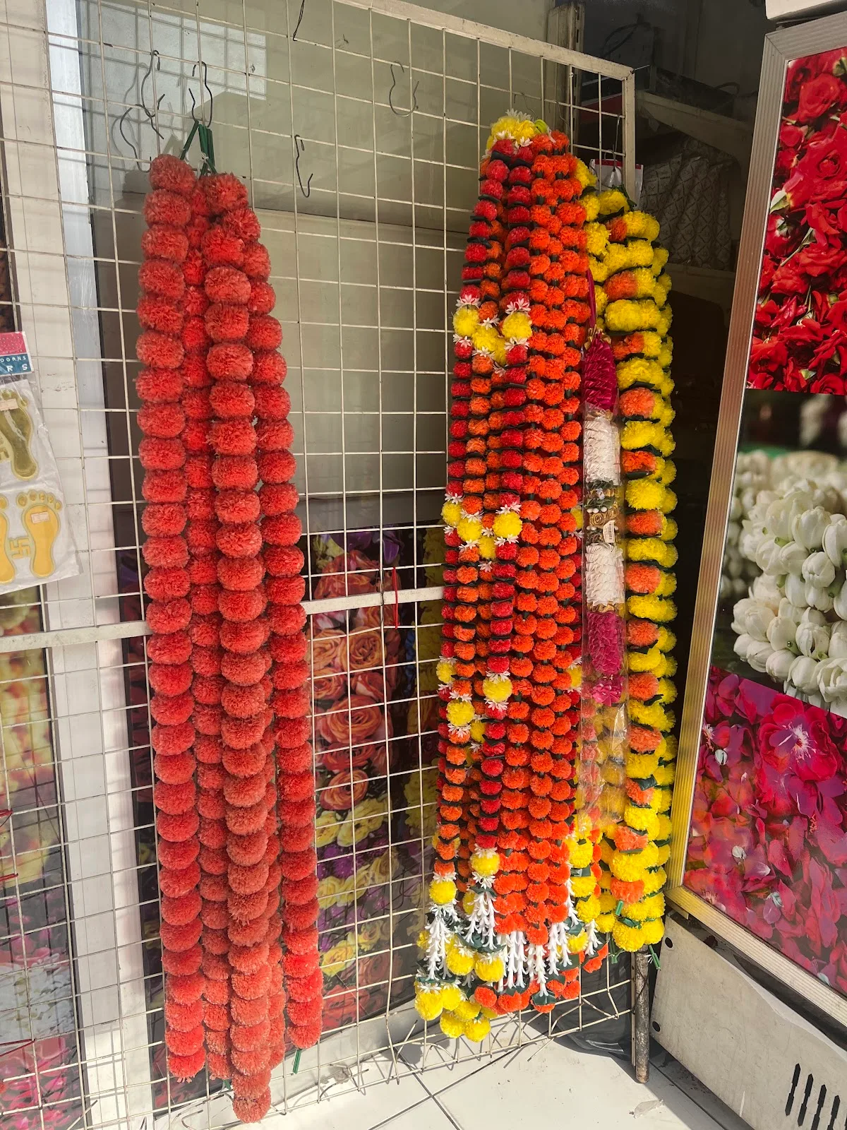 Hand-strung flower garlands in marigold, rose and jasmine hanging on a display rack at Perumal Flowers.