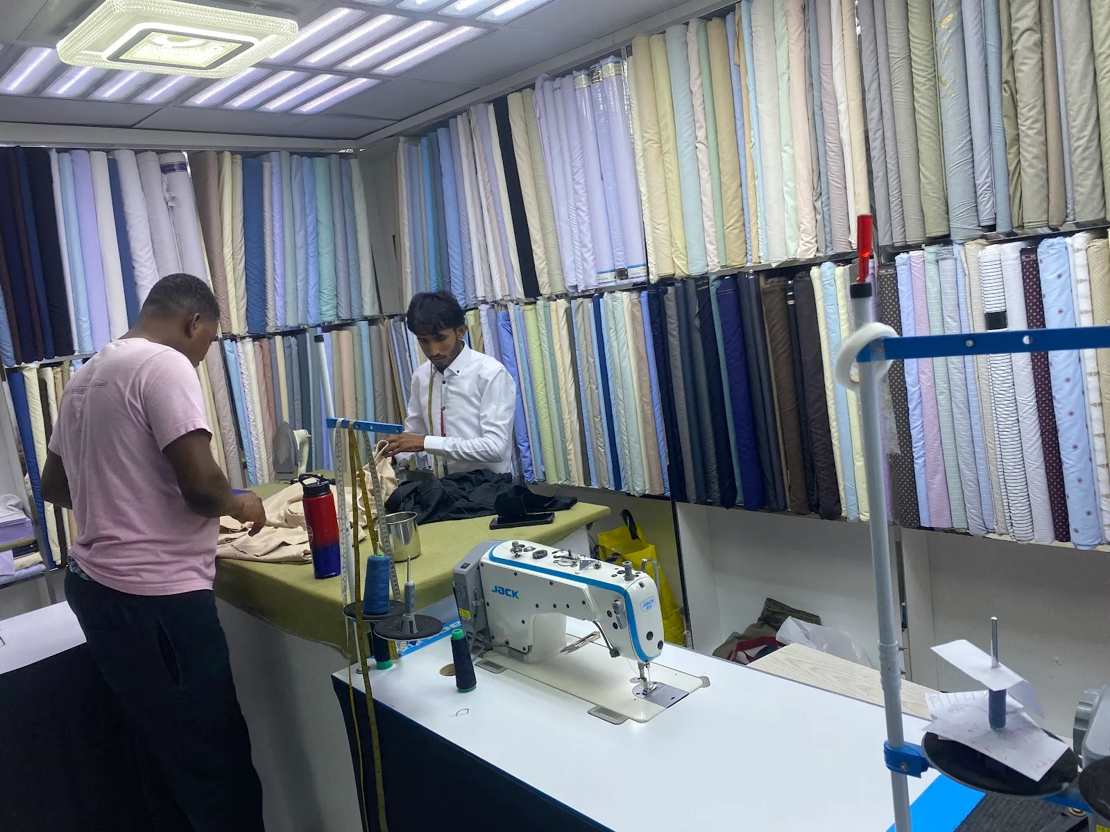 Tailor measuring fabric at a JACK sewing machine in the workshop