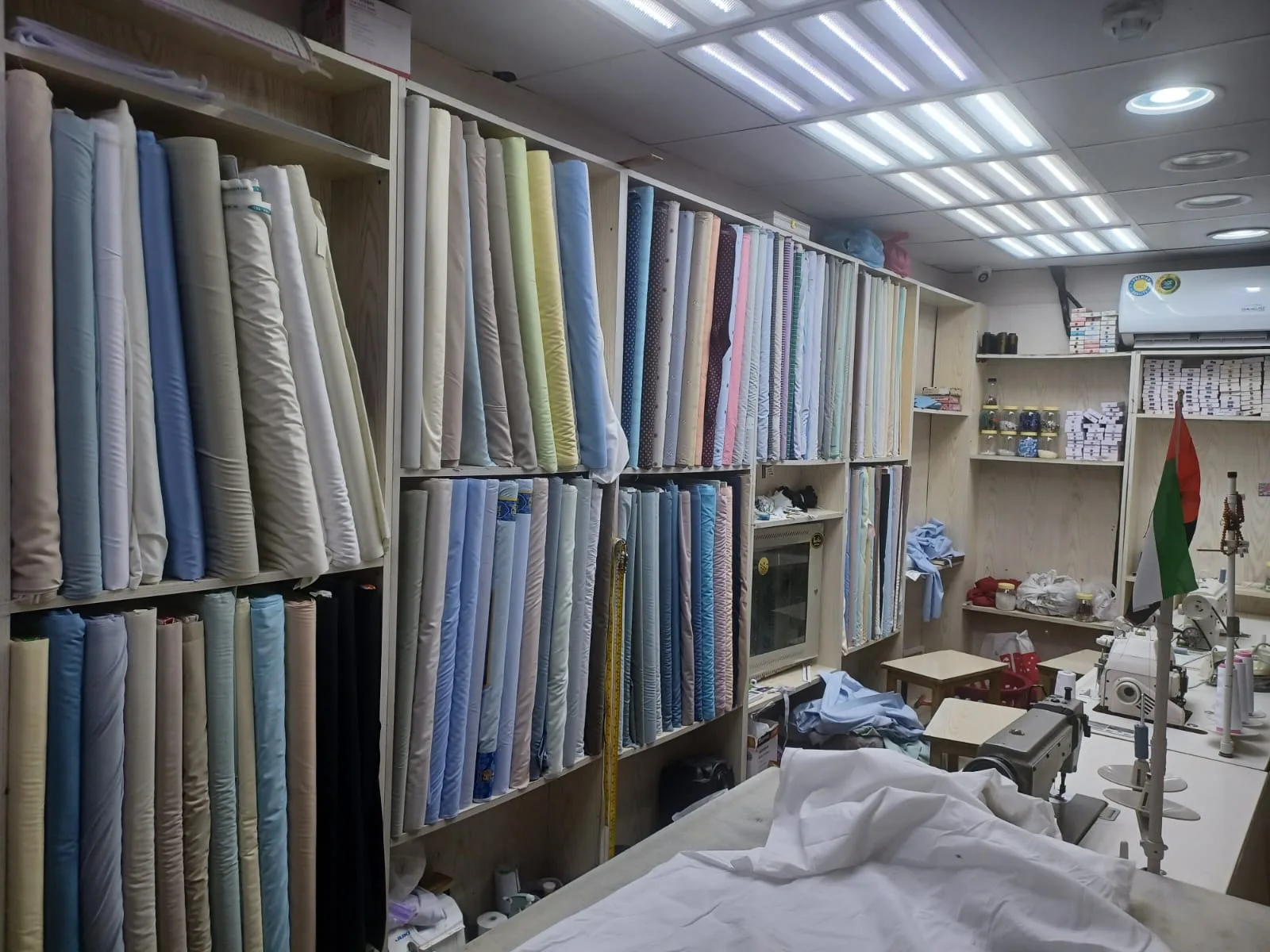 Floor-to-ceiling shelves of folded fabric bolts in the tailoring workshop