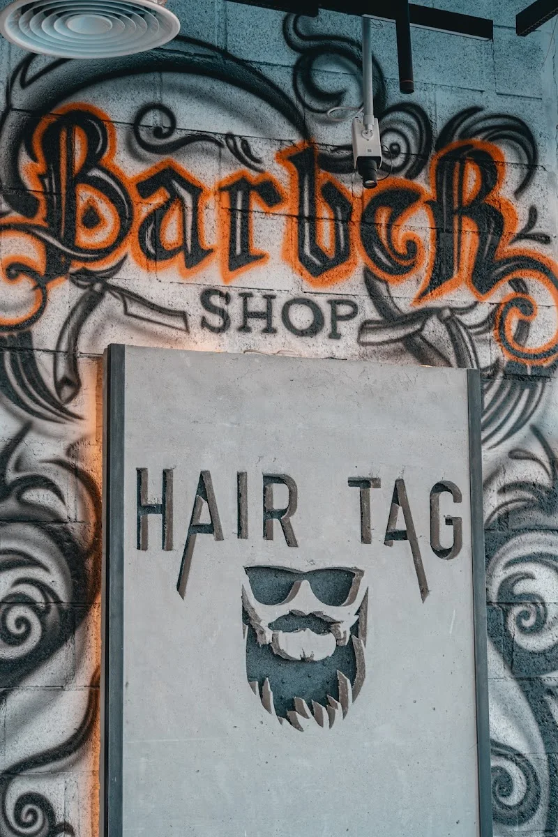 The Hair Tag logo and beard mark carved into a concrete signage wall