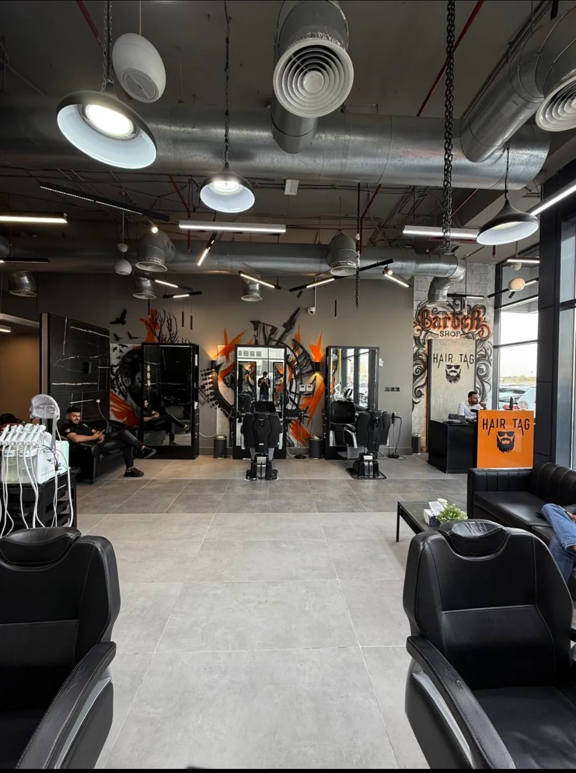 Inside Hair Tag Gents' Salon in Al Jaddaf — barber chairs, mirrors and orange graffiti murals