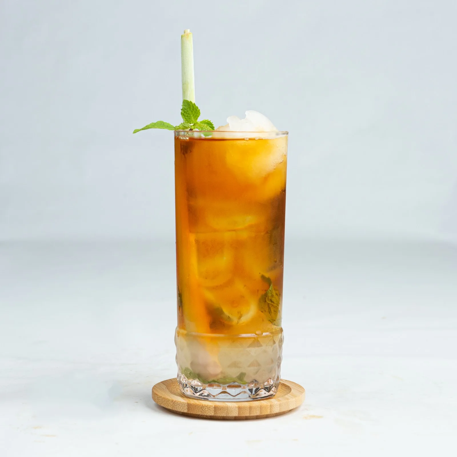 Tall glass of iced lemongrass tea garnished with mint