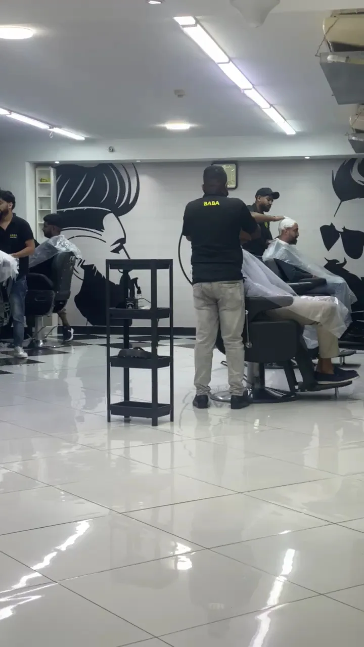 BABA barbers cutting hair beside the signature moustache wall mural