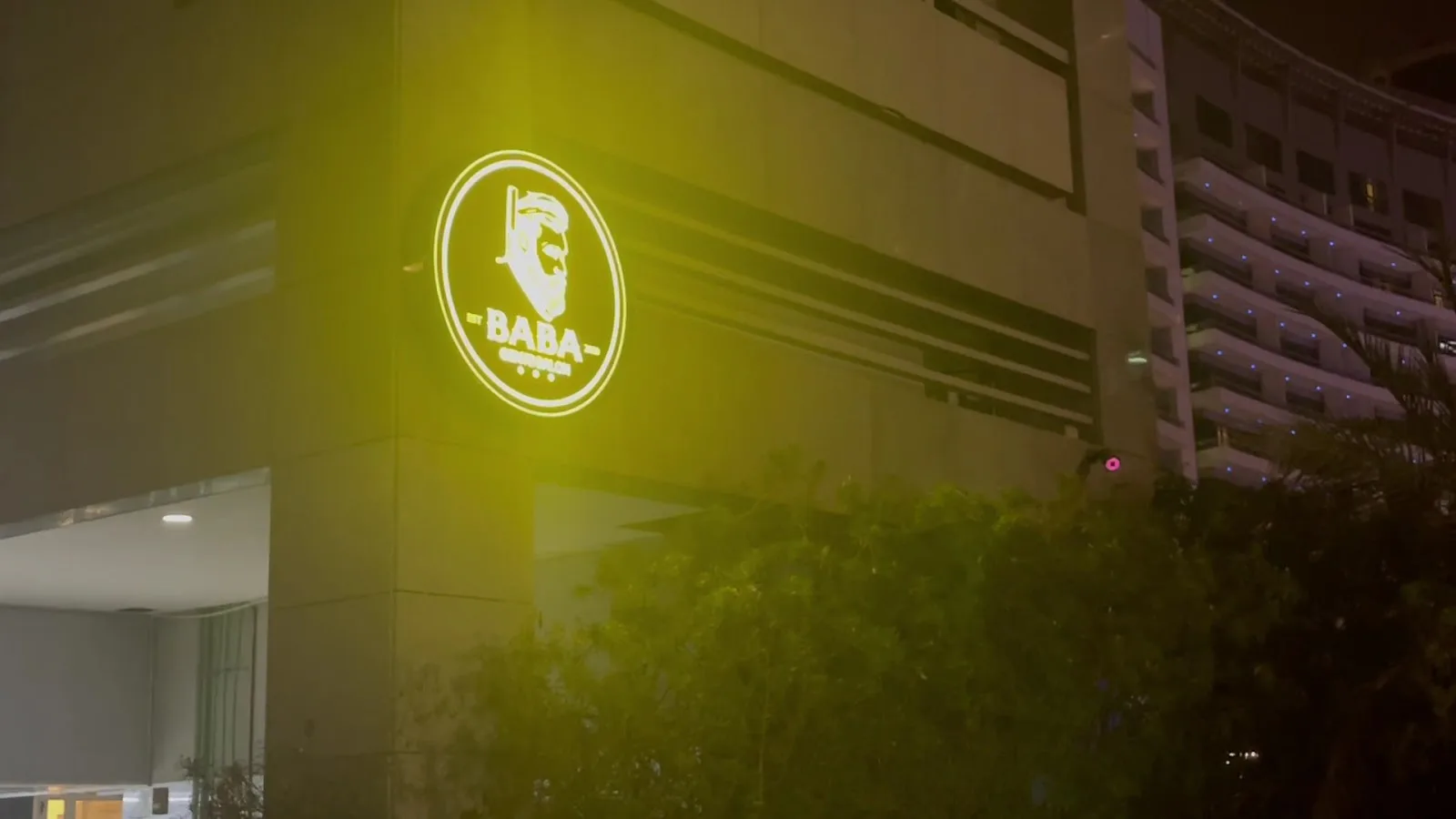 Illuminated round BABA logo on the building exterior at night