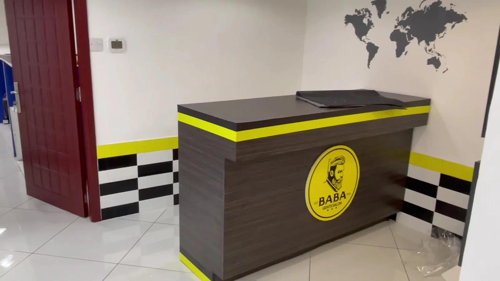 BABA Gents Salon reception desk with the round logo and world-map wall