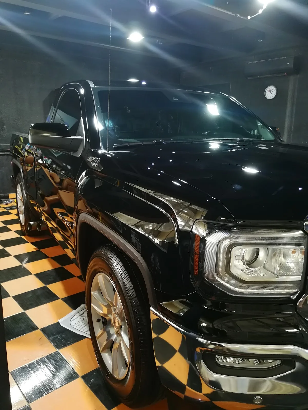 A glossy black GMC pickup after detailing in the workshop