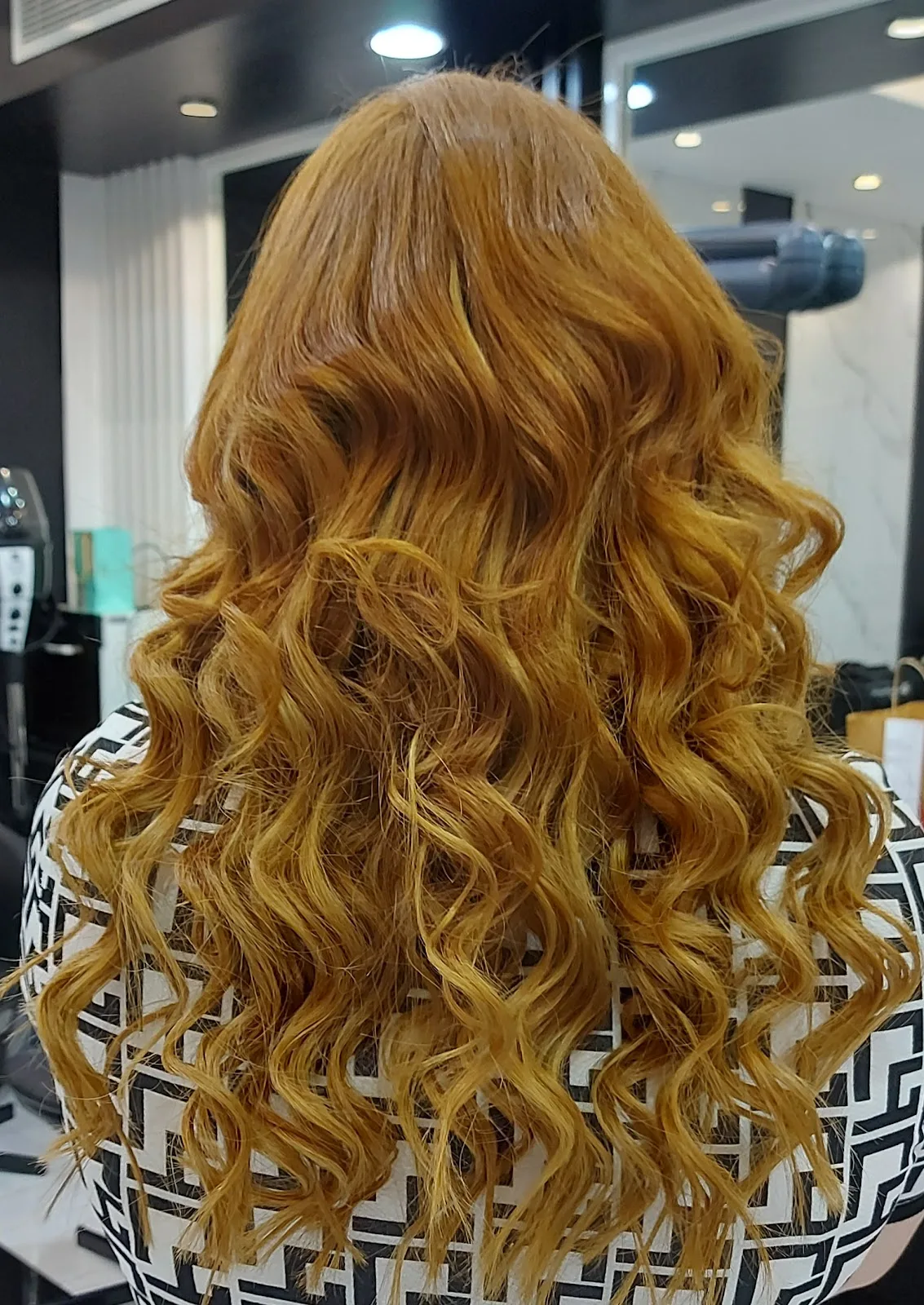 Long copper-blonde hair styled into soft curls
