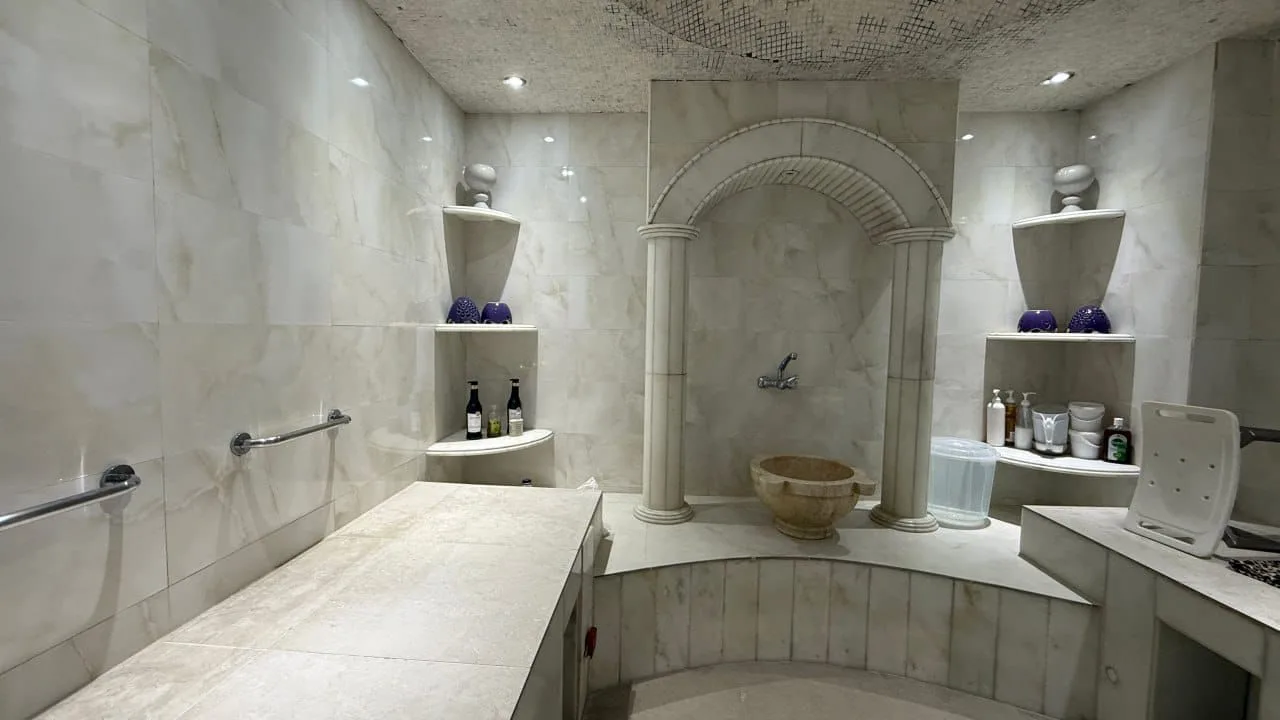 The salon's private marble hammam steam room with an arched stone fountain