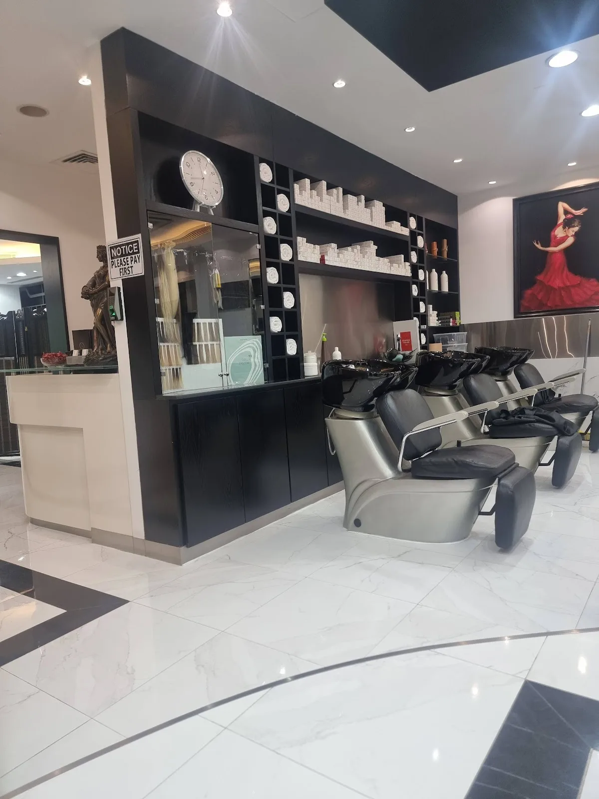 The hair wash and styling bar at Al Marfa Star, with black basins, white marble floor and framed artwork