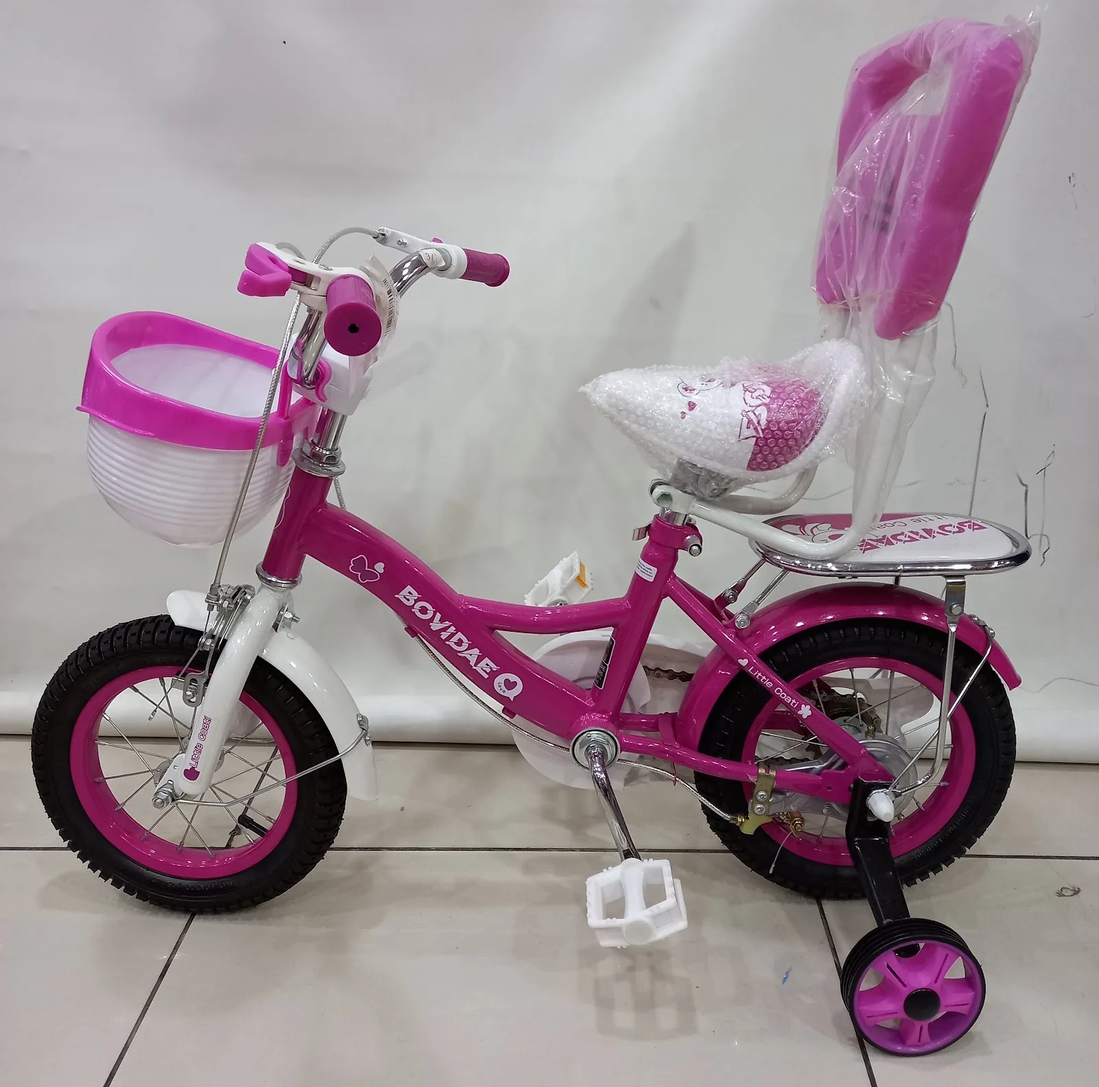 Pink children's bicycle with basket and training wheels, available in store