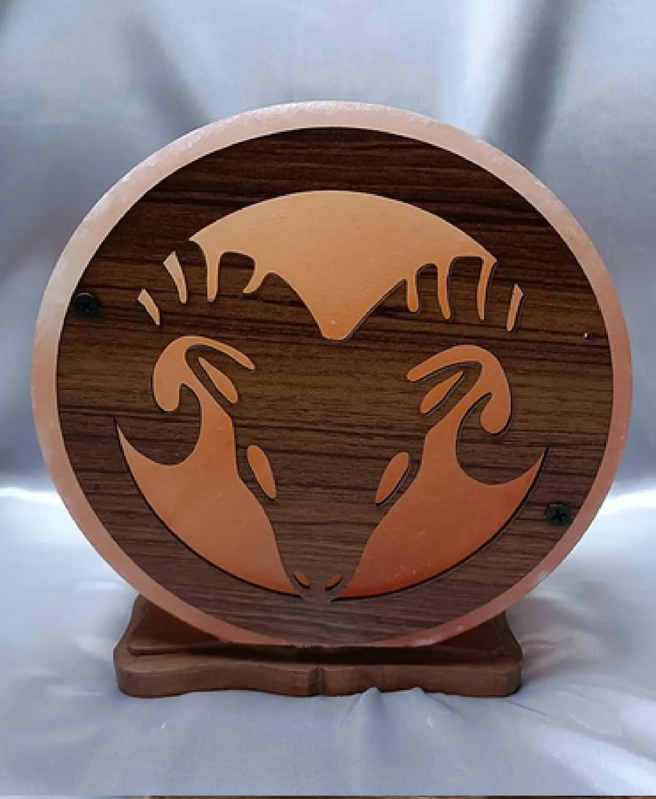 Round Himalayan salt lamp with a carved wooden zodiac ram design