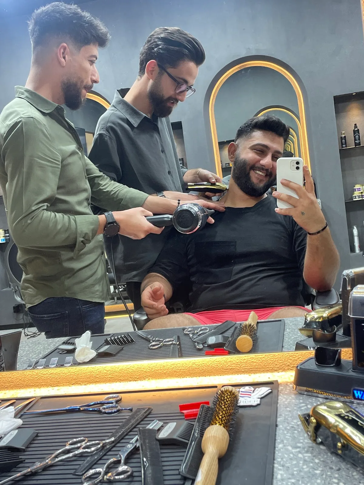 Two Diveno barbers finishing a smiling client's cut