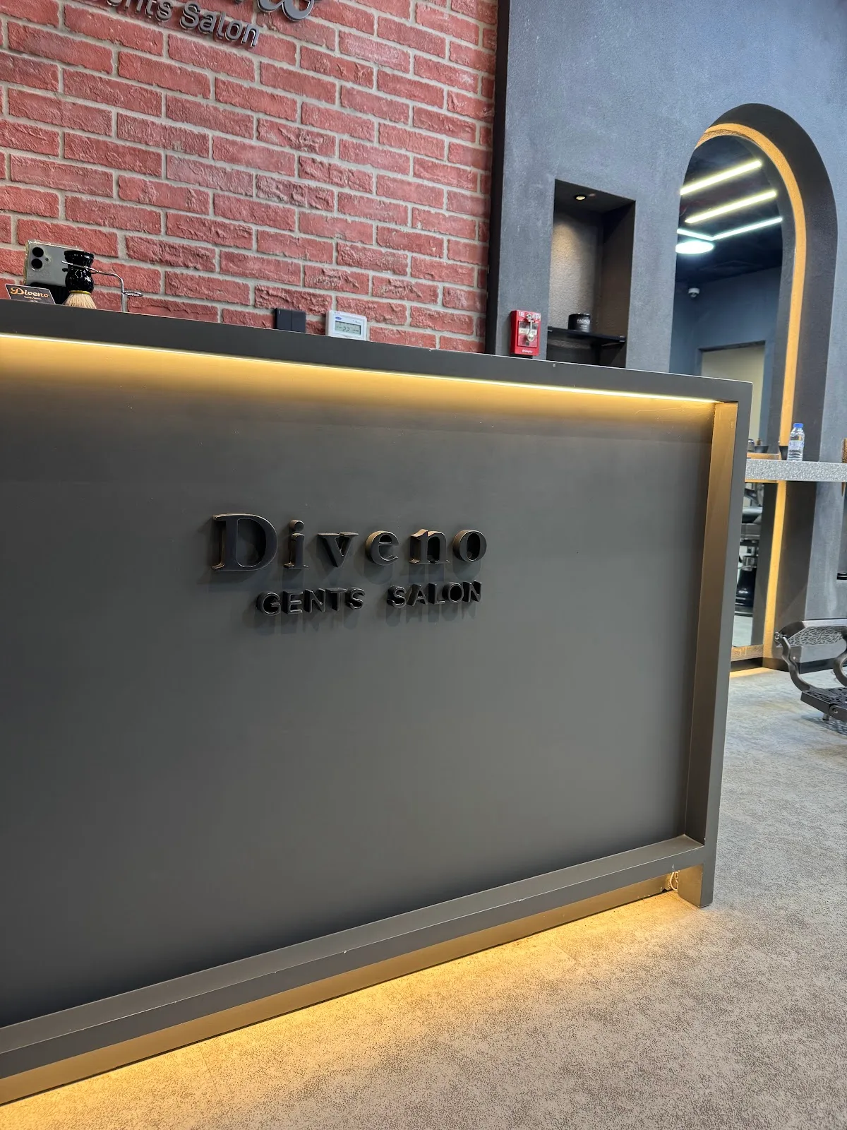 Diveno Gents Salon reception desk with brick wall and gold-lit edge