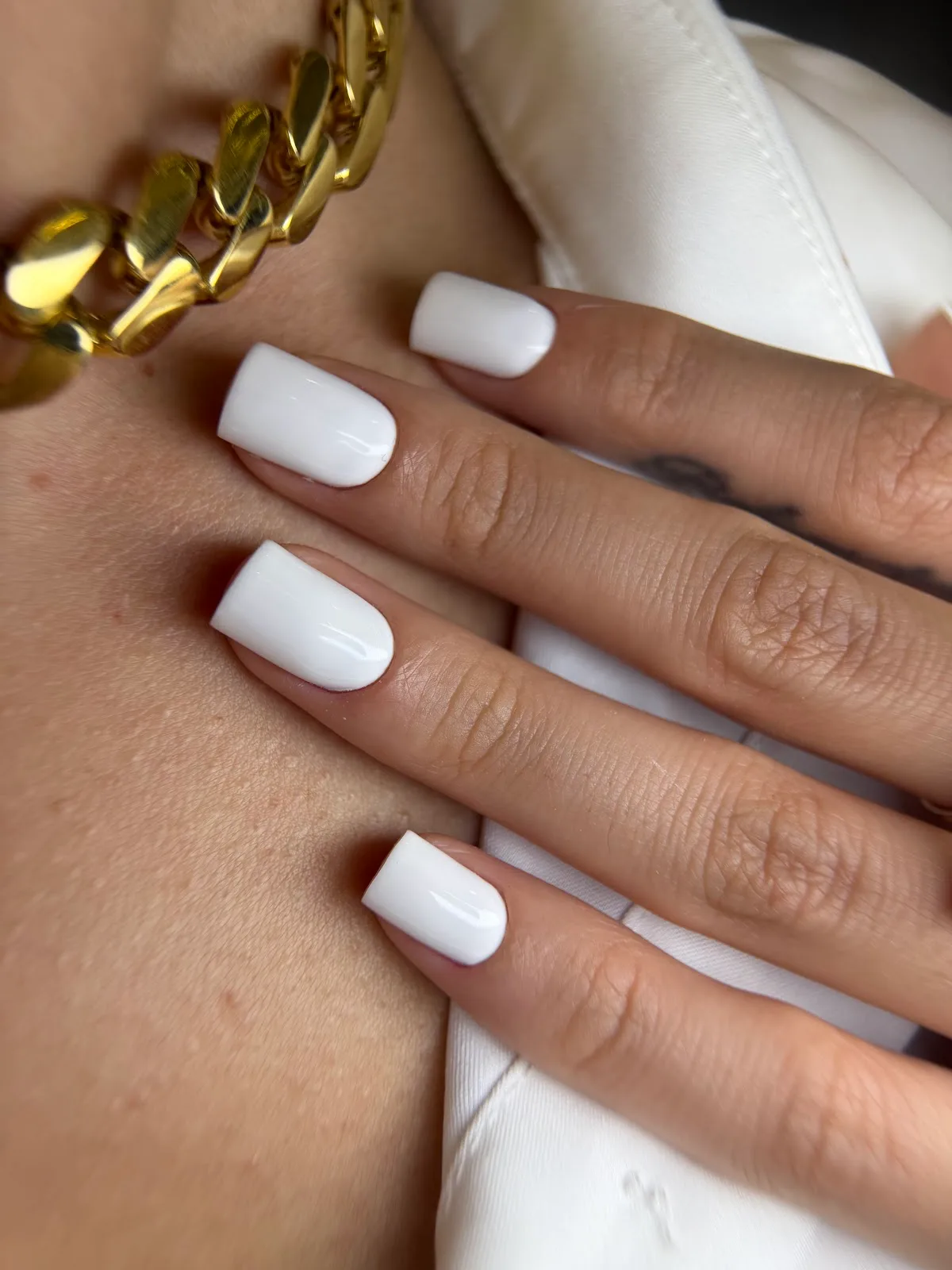 Crisp white square manicure with gold jewellery