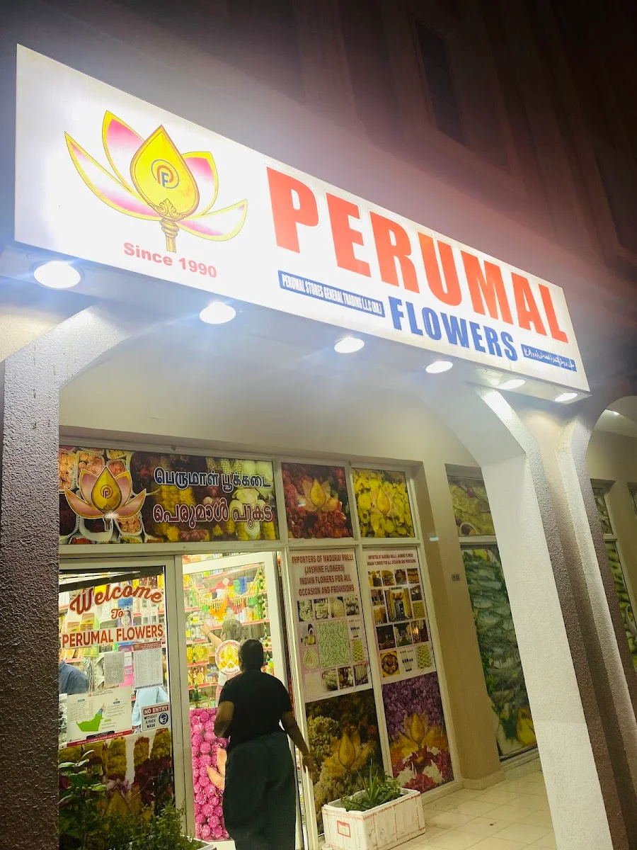 Perumal Flowers storefront at night in Dubai International City, the lotus sign lit above the entrance