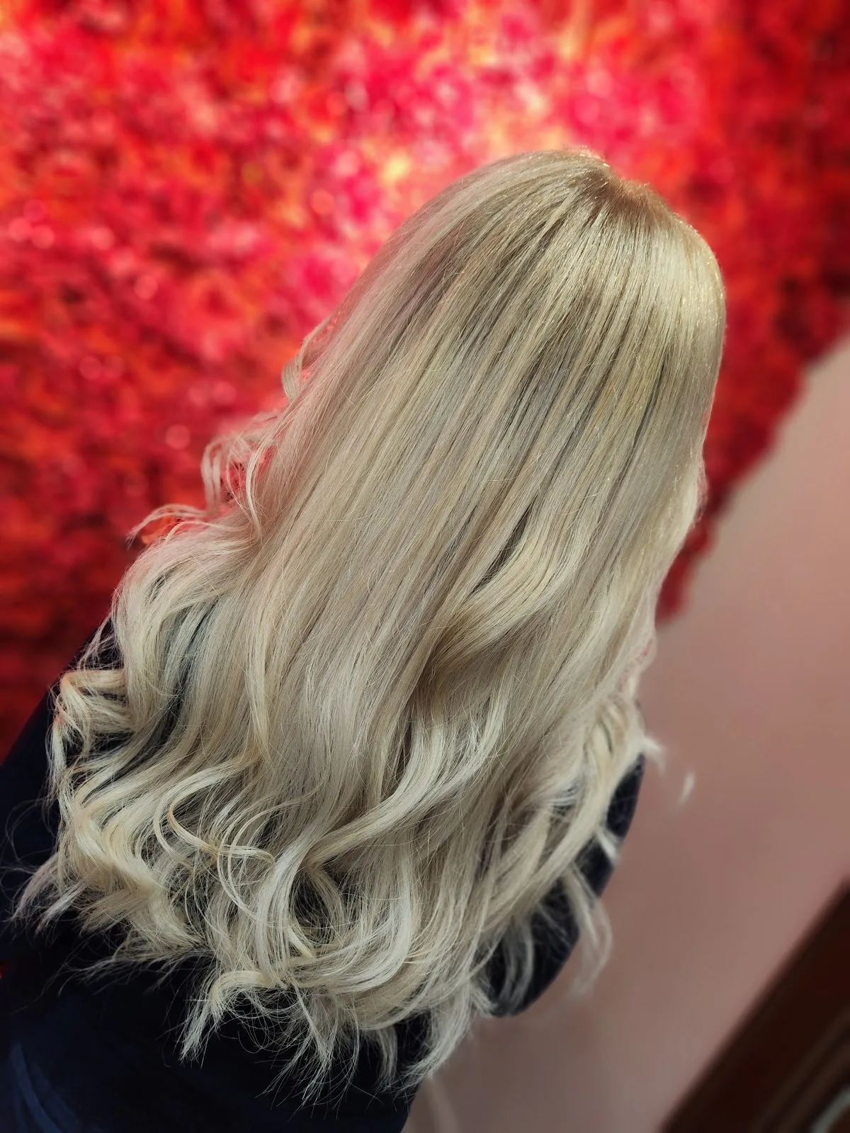 Blonde waves styled in front of a red flower wall