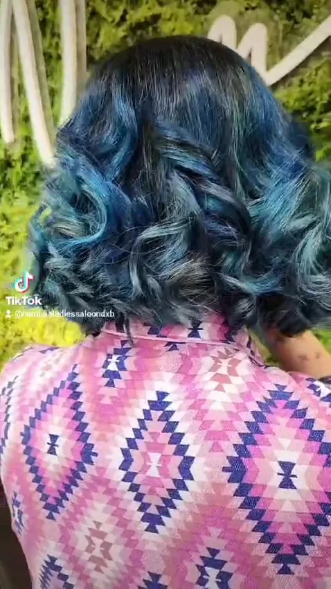 Blue-toned curls styled in front of the Numidia greenery wall