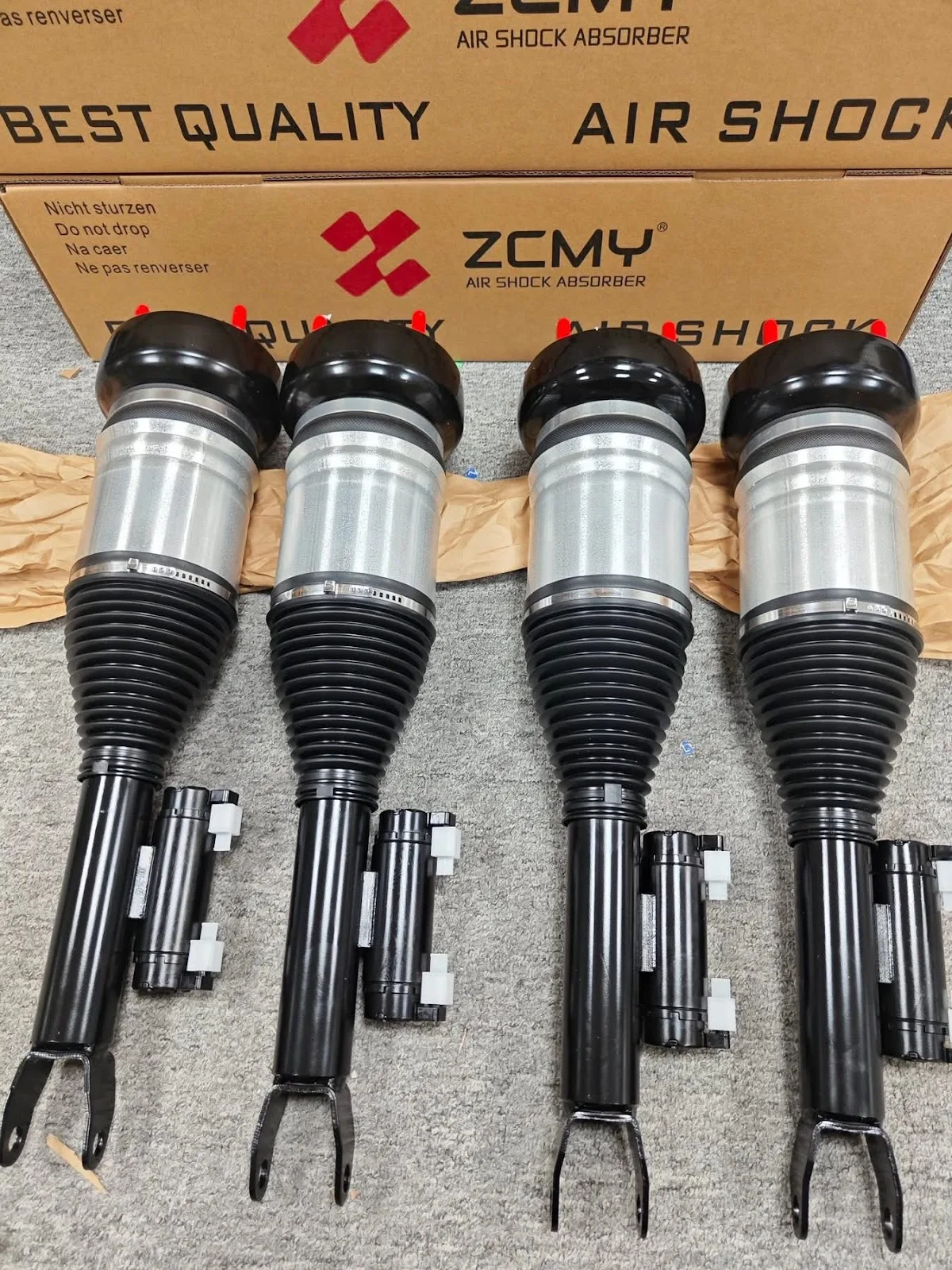 Four new air shock absorbers from ZCMY laid out on the workshop floor ready to fit