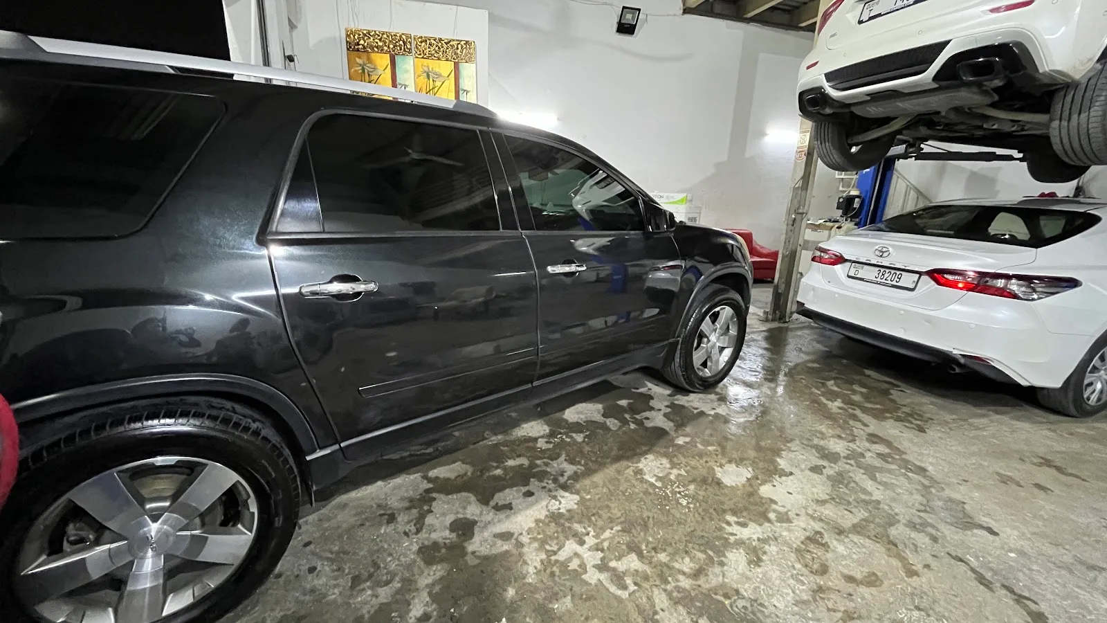Two vehicles being serviced at once inside Bindarwash Garage, one raised on a lift