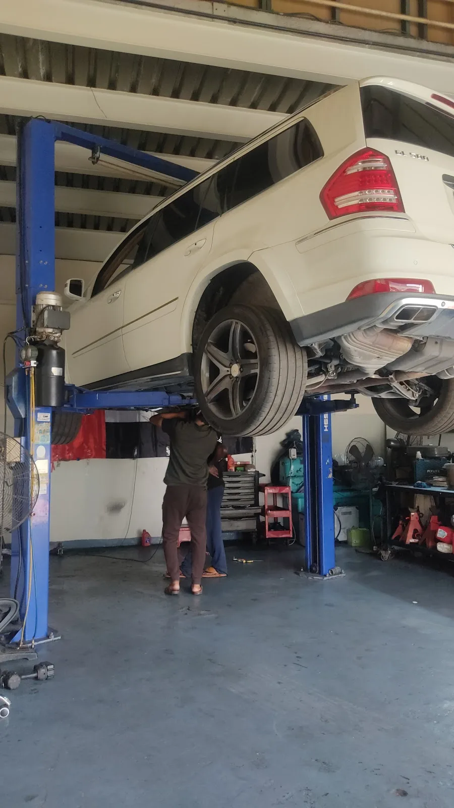 A white Mercedes-Benz GL SUV raised on a lift for underbody inspection