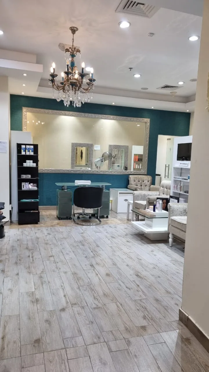 Reception area at Aroushi Beauty Salon with chandelier and teal accent wall