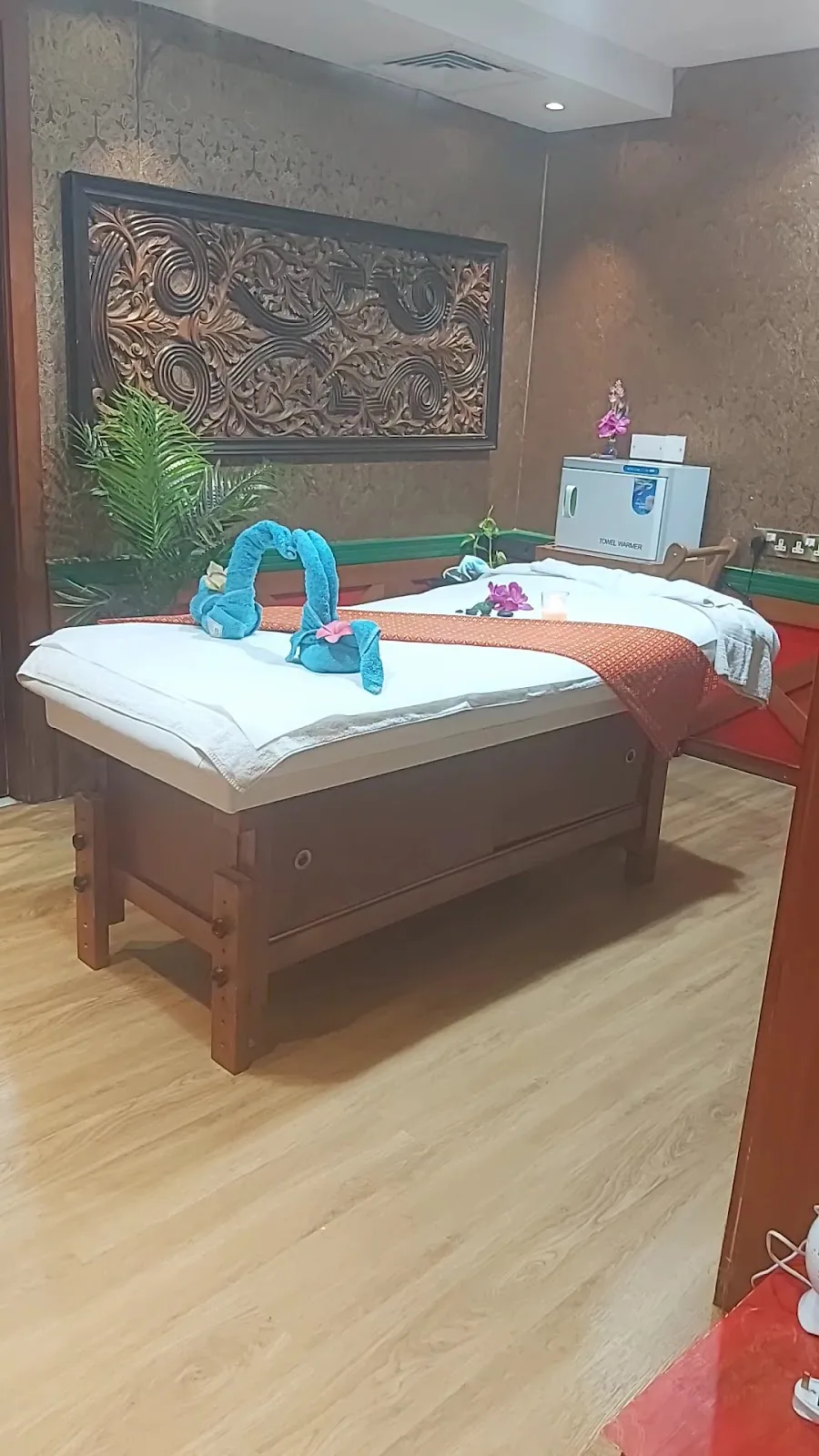 Private spa massage room at Aroushi Beauty Salon with carved wood panel and warm towels