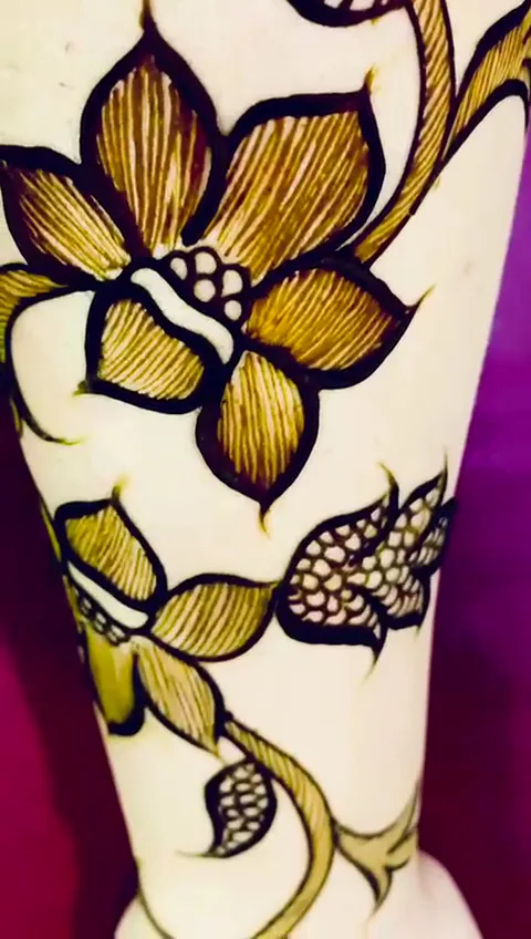 Intricate floral henna design in golden tones on an arm