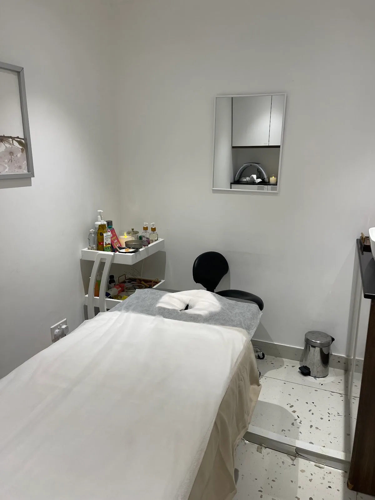 Clean white facial treatment room with a draped bed