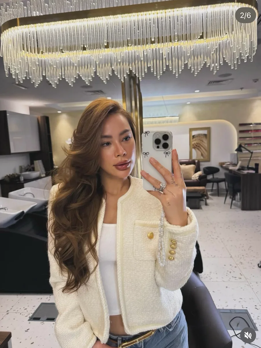 Guest in a cream tweed jacket in the salon mirror beneath the chandelier