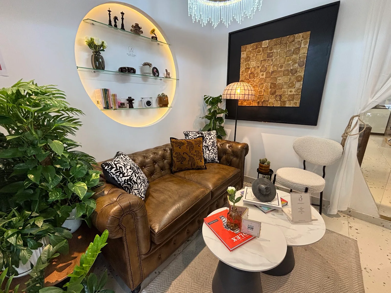 Blonde Studio waiting lounge with chesterfield sofa, lit circular shelf and greenery