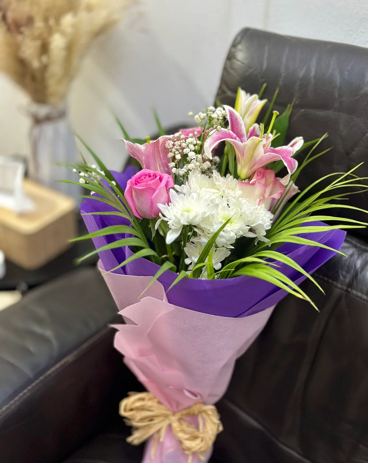 Pink lily and rose bouquet wrapped in purple
