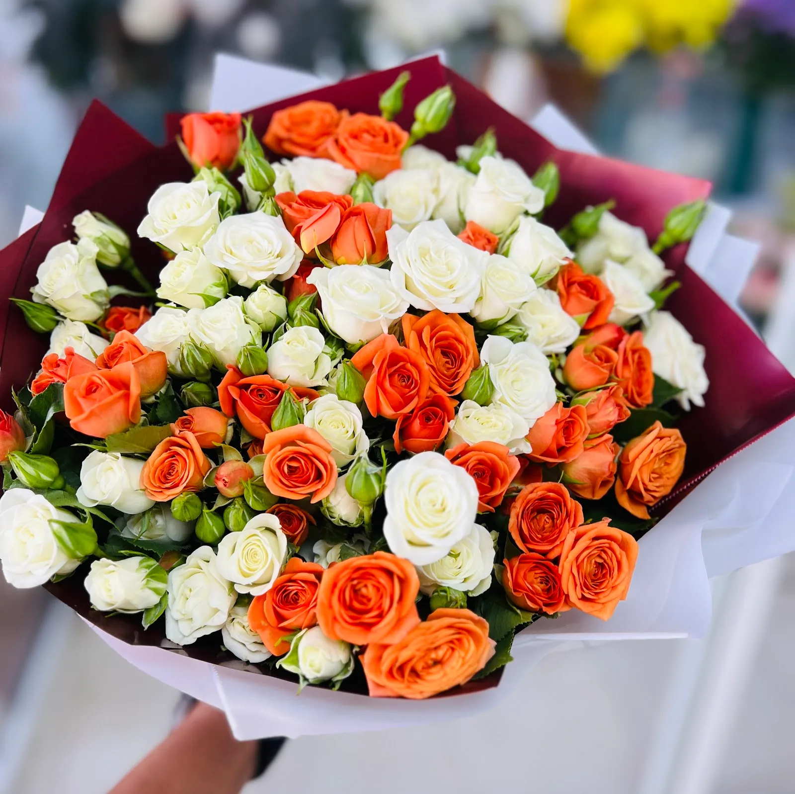 Hand-tied bouquet of orange and white roses wrapped at Snowdrop Flowers