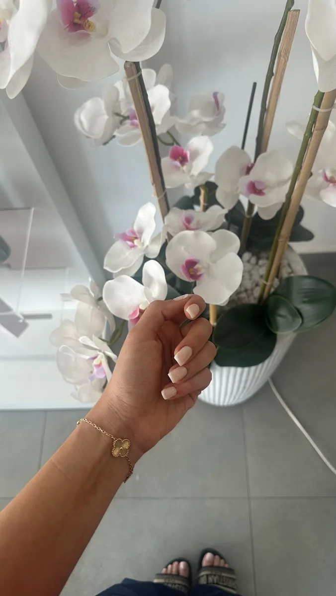 Nude manicure beside white orchids