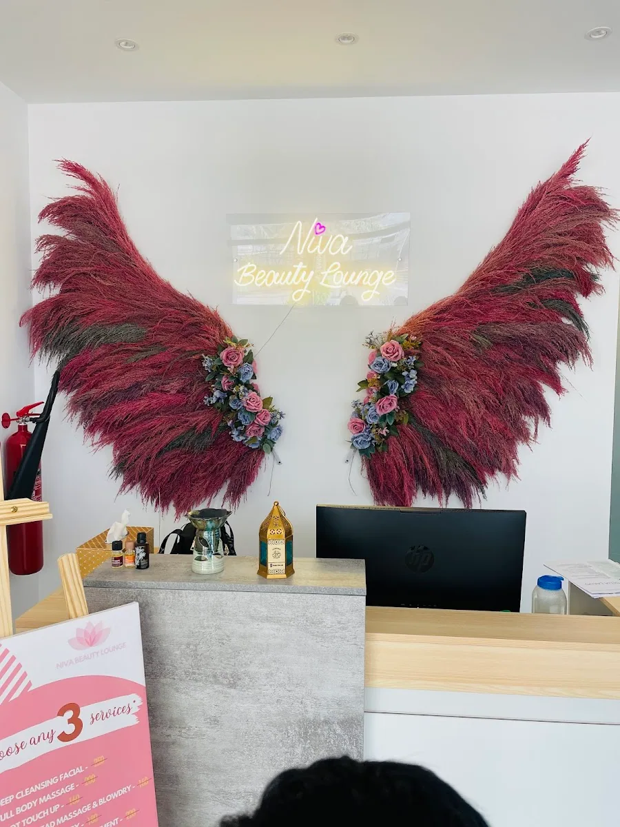 Reception of Niva Beauty Lounge with its signature burgundy pampas-grass wings and neon name sign