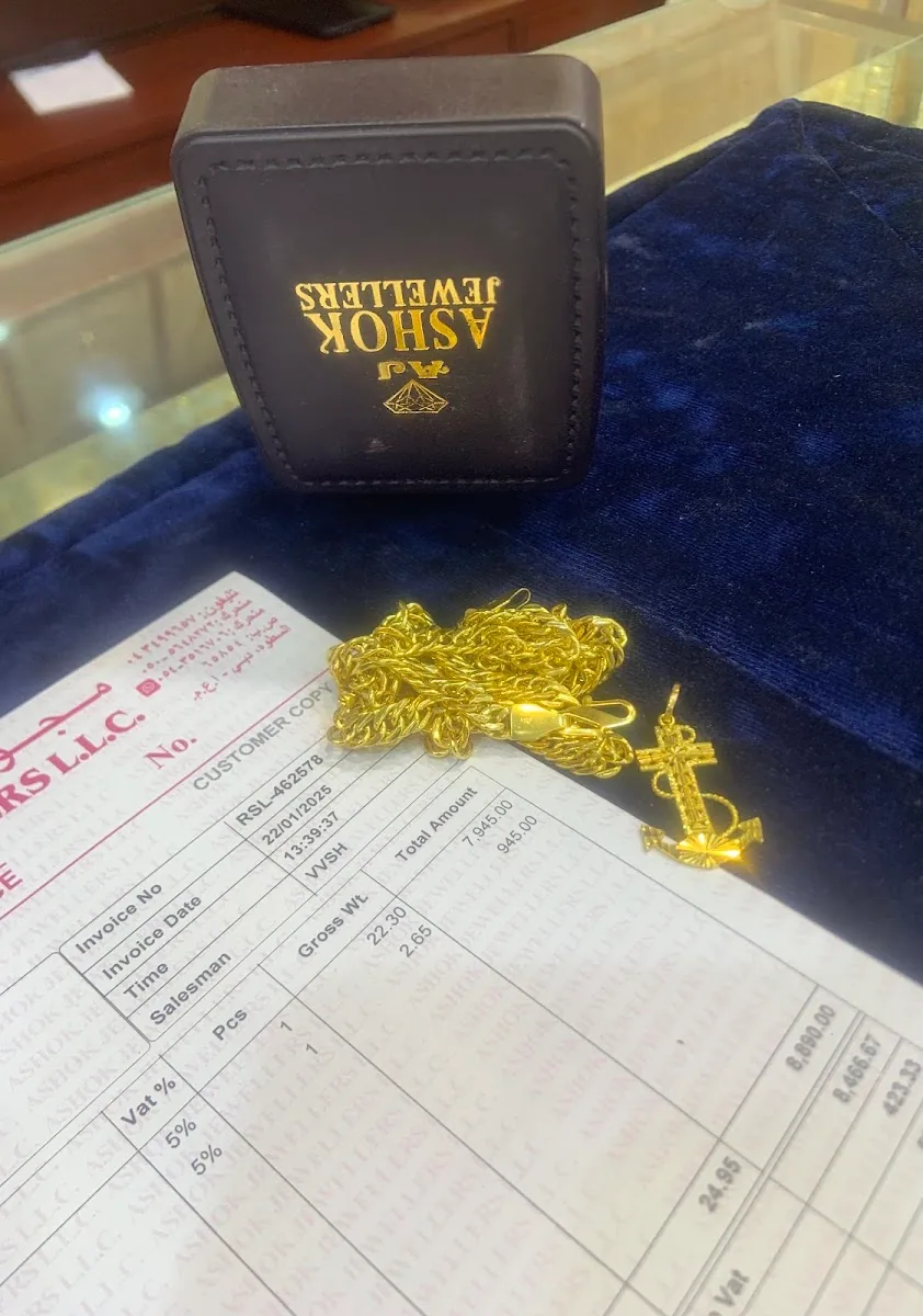 Gold rope chain with anchor pendant beside an Ashok Jewellers branded box and invoice