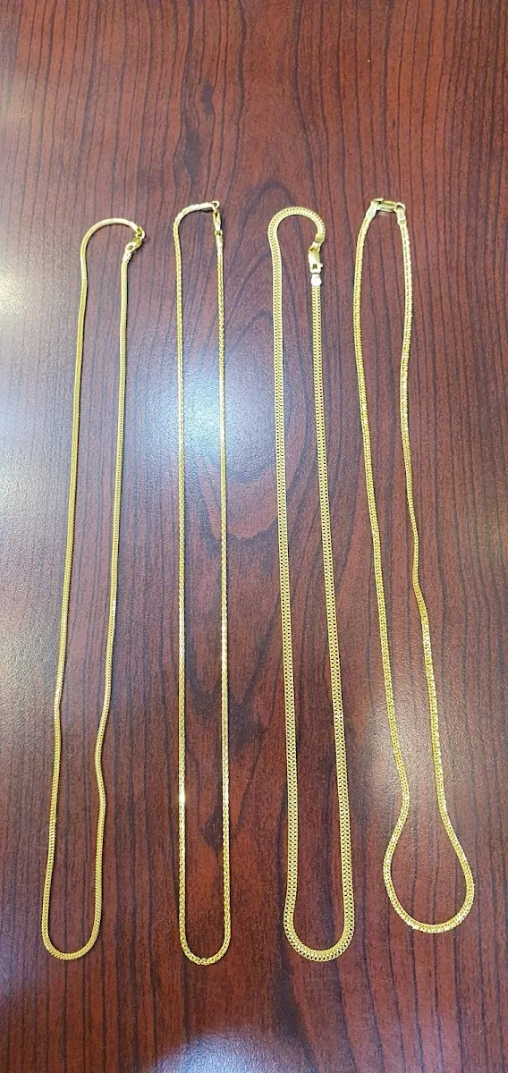 Four fine gold chains laid out on a wooden surface