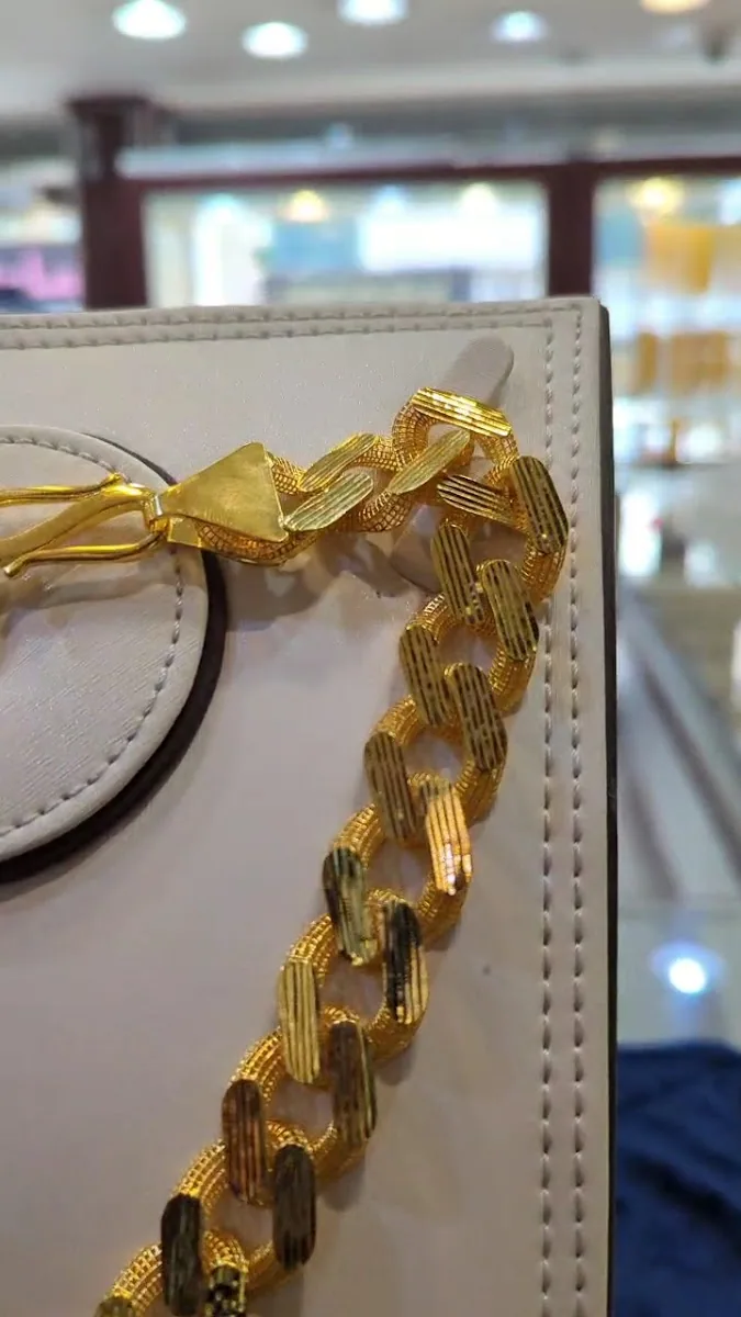 Macro close-up of a heavy textured gold curb-link bracelet