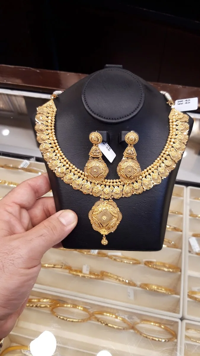Intricate 22-carat gold necklace and earring set displayed on a black bust