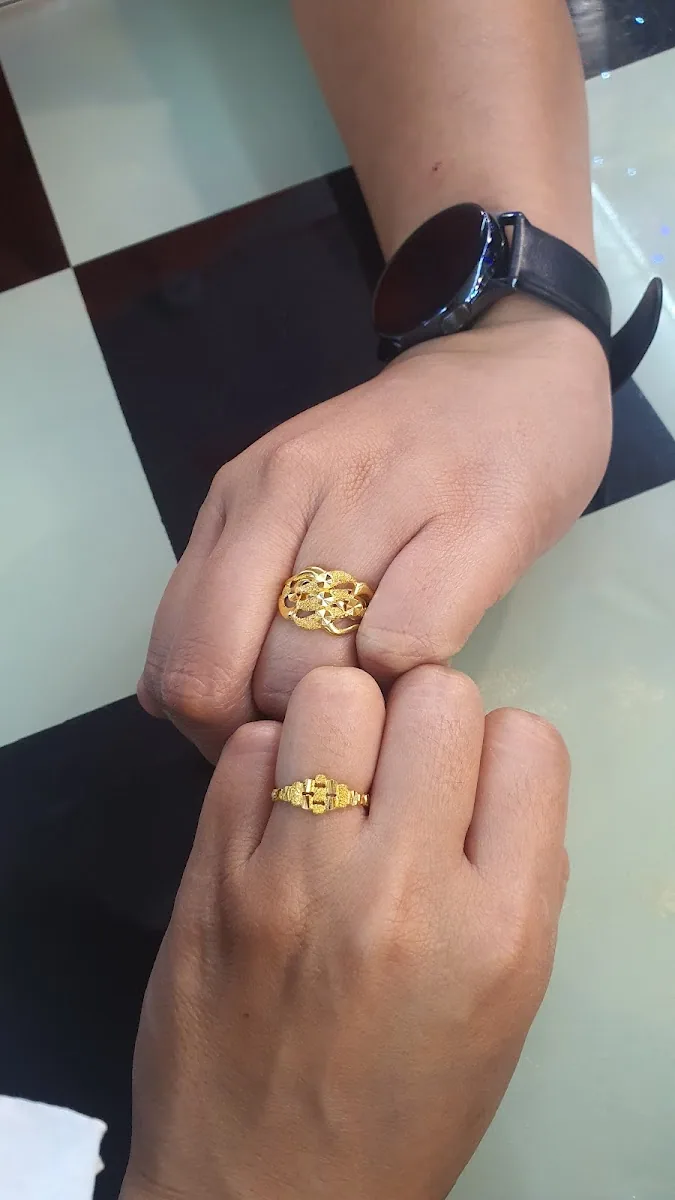 Two hands wearing detailed gold rings at the Ashok Jewellers counter