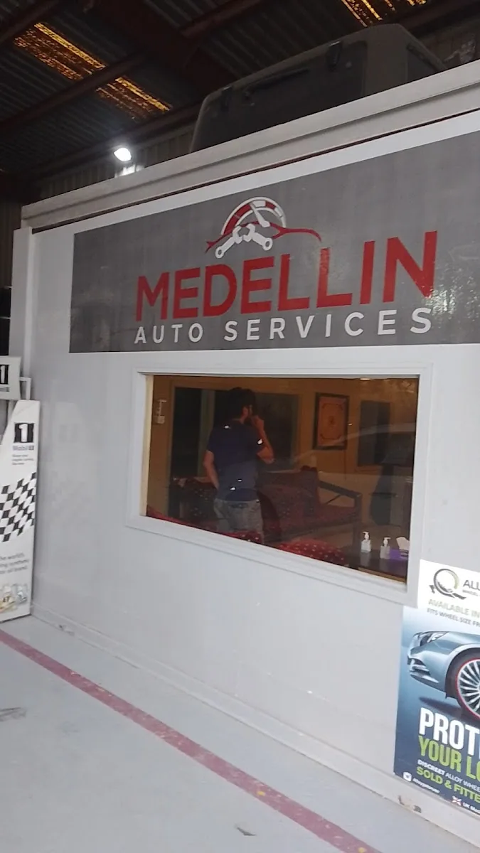 The Medellin Auto Services sign mounted above the service window inside the garage